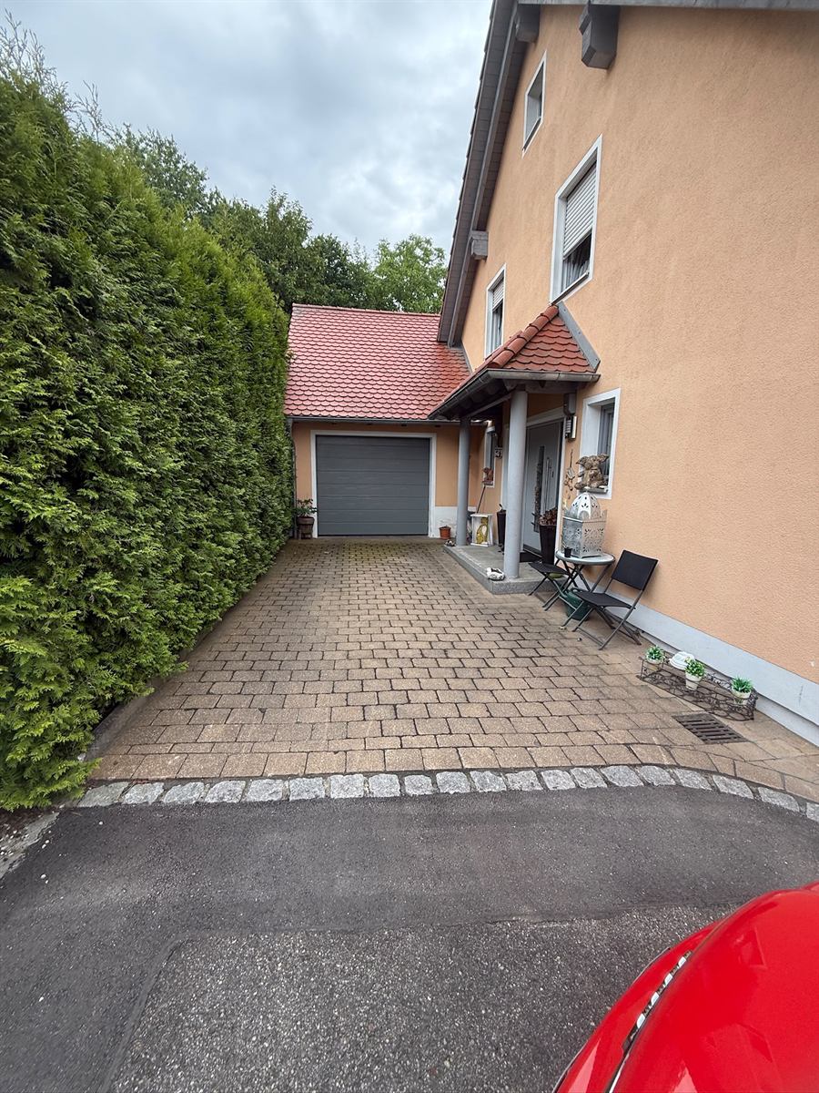 Pflastereinfahrt vor der Pflasterreinigung: dunkle Steine und vermooste Fugen vor der Garage