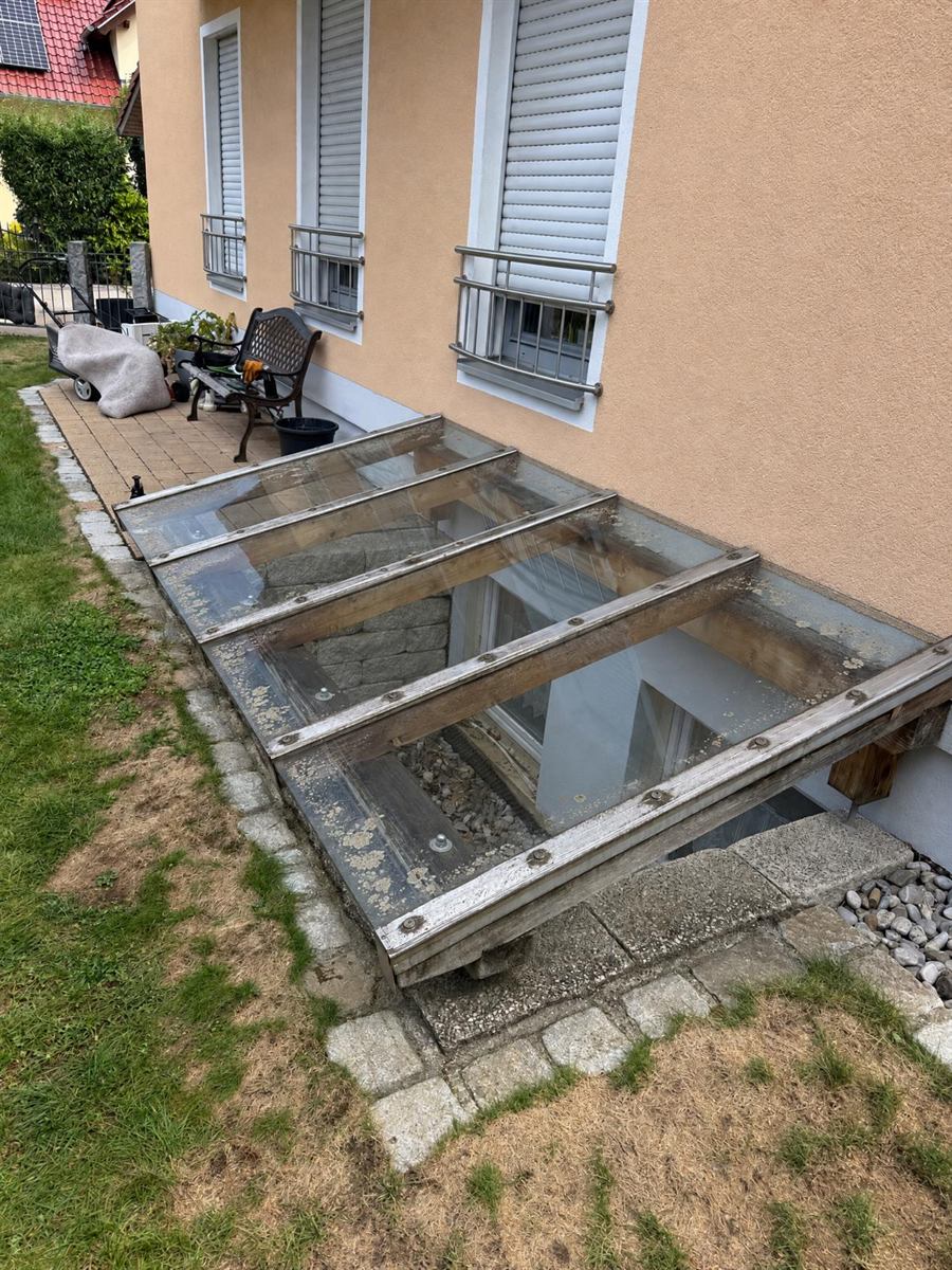 Verschmutztes Glasdach über einem Kellerabgang vor der Glasreinigung