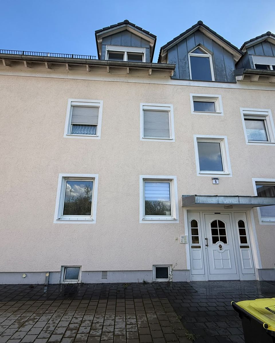 Fassadenreinigung: helle Putzfassade eines Mehrfamilienhauses mit Gauben nach der Reinigung