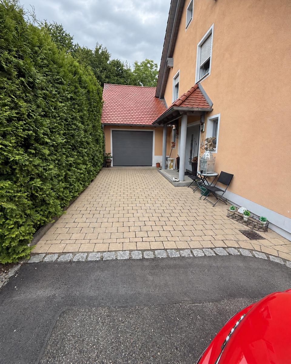 Pflasterreinigung: helle, gereinigte Hofeinfahrt mit Garage und Hecke